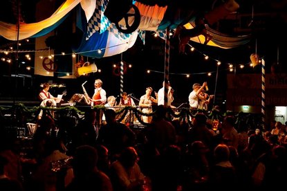 Eine Band spielt auf einer kleinen Zeltbühne auf einem Oktoberfest