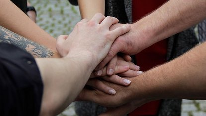 Geste für Team-Zusammenhalt: Hände zur Mitte, übereinander gelegt
